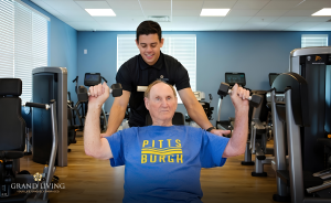 Grand Living Fitness Director helping a resident with strength training.